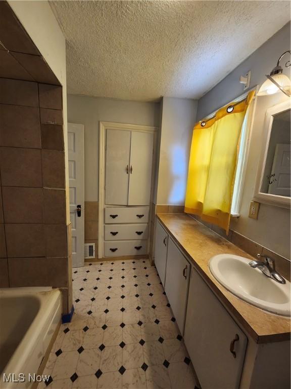 bathroom featuring vanity, a bathing tub, and a textured ceiling