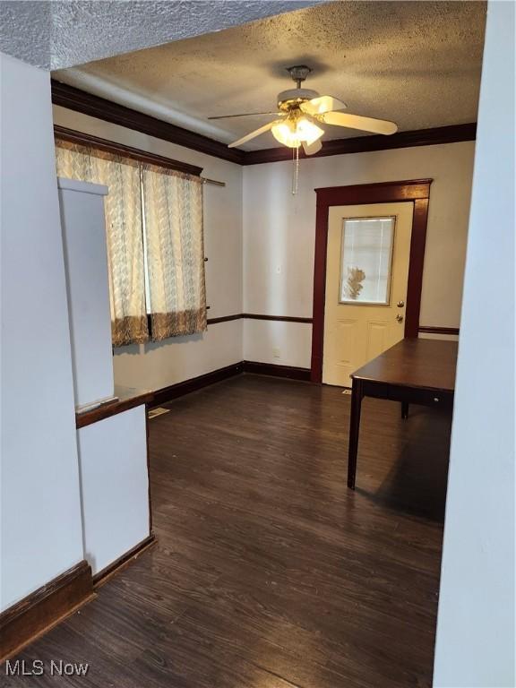 interior space with ceiling fan, ornamental molding, dark hardwood / wood-style flooring, and a textured ceiling