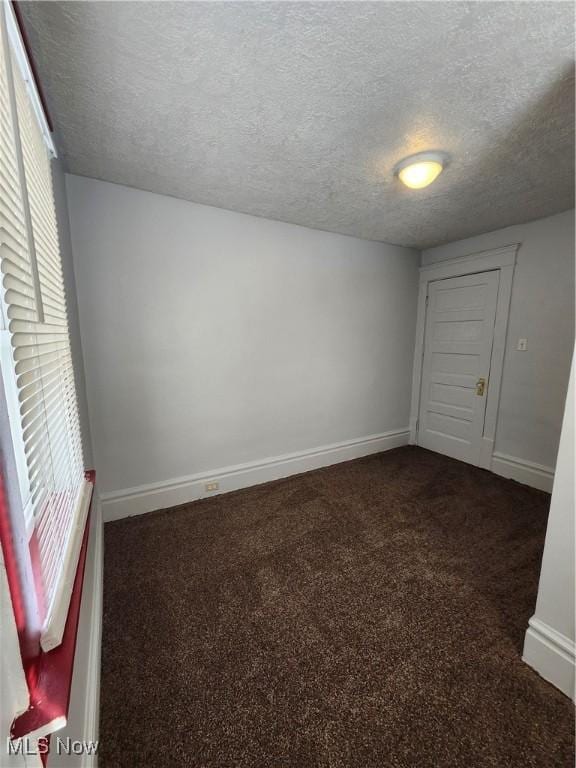 unfurnished bedroom with dark colored carpet and a textured ceiling