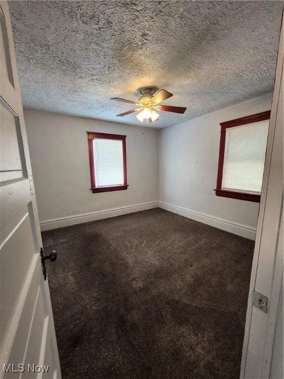 unfurnished room with dark carpet, a textured ceiling, and ceiling fan