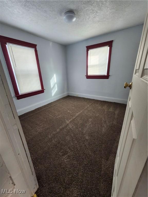 carpeted empty room featuring a textured ceiling