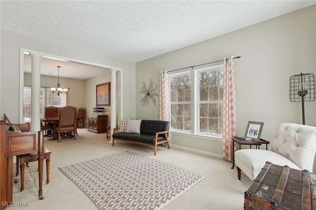 living area featuring decorative columns, plenty of natural light, light carpet, and an inviting chandelier