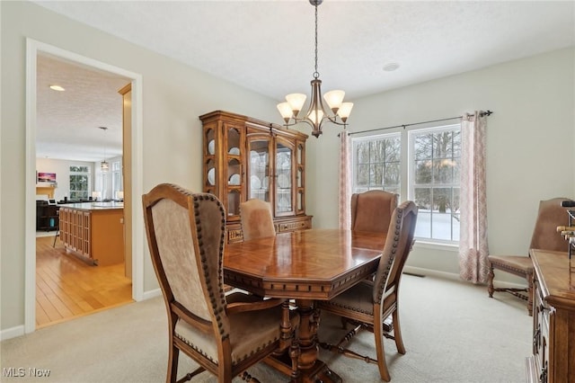 carpeted dining area with a textured ceiling and a chandelier