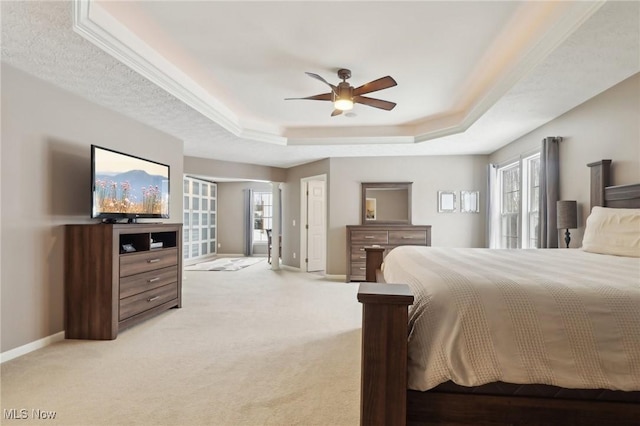 carpeted bedroom with a tray ceiling and ceiling fan