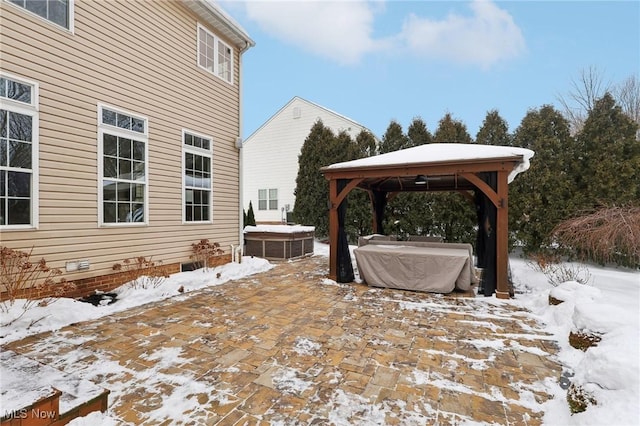 snow covered patio with a gazebo and a hot tub