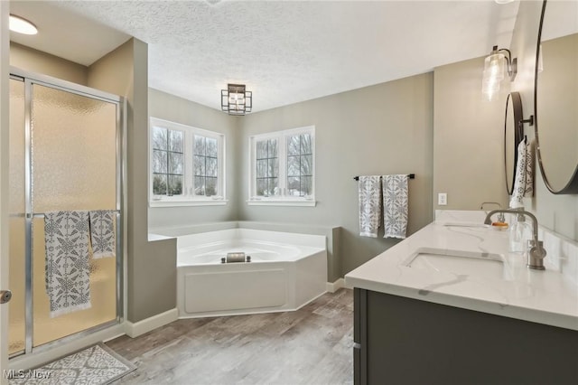 bathroom featuring vanity, hardwood / wood-style floors, independent shower and bath, and a textured ceiling