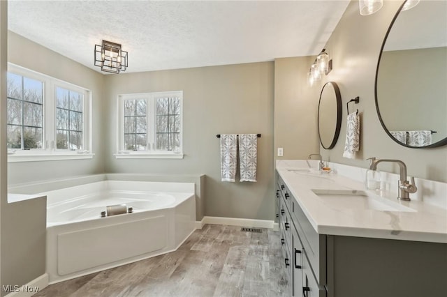 bathroom featuring a tub to relax in, vanity, hardwood / wood-style floors, and a textured ceiling