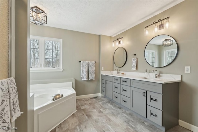 bathroom featuring vanity, hardwood / wood-style floors, a textured ceiling, and a tub to relax in