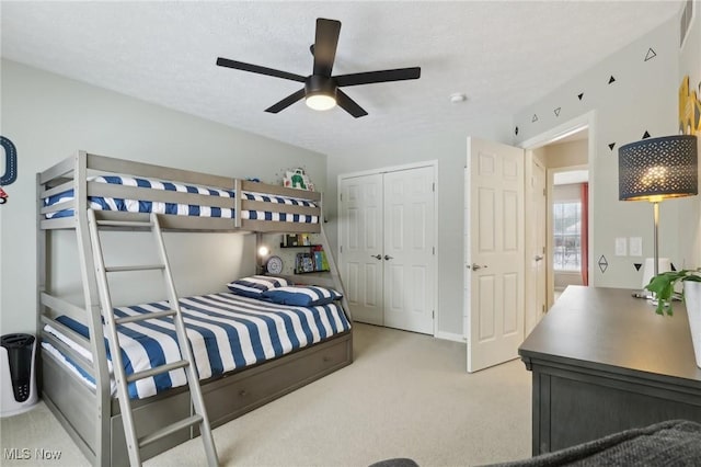 carpeted bedroom with a textured ceiling, a closet, and ceiling fan