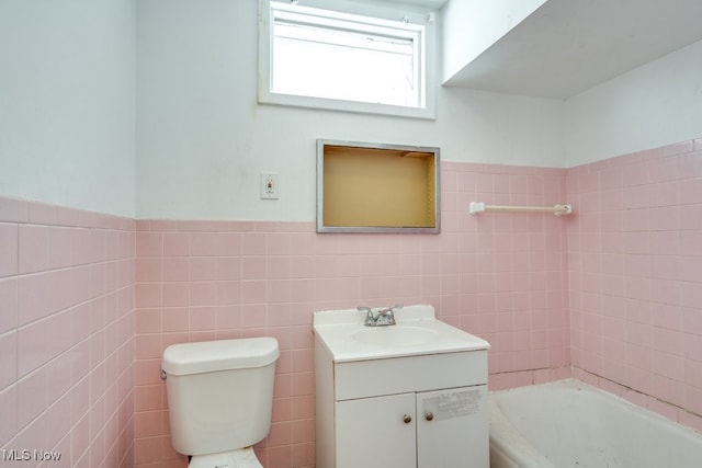 bathroom with vanity, a bathtub, tile walls, and toilet