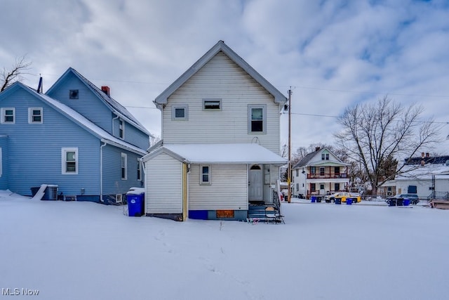 snow covered back of property with central AC