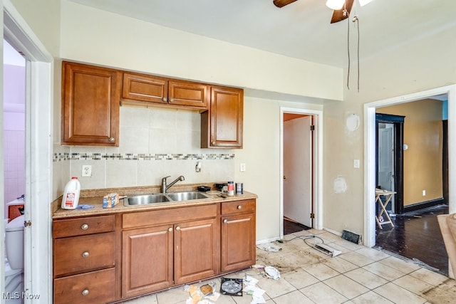 kitchen featuring backsplash, light tile patterned floors, sink, and ceiling fan