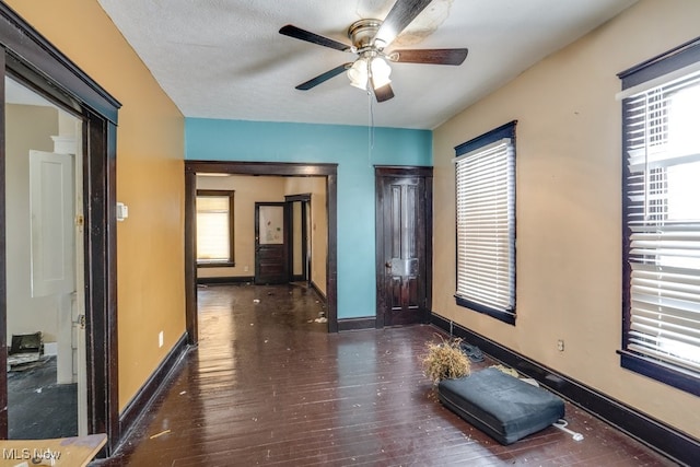 interior space with ceiling fan, a textured ceiling, and dark hardwood / wood-style flooring