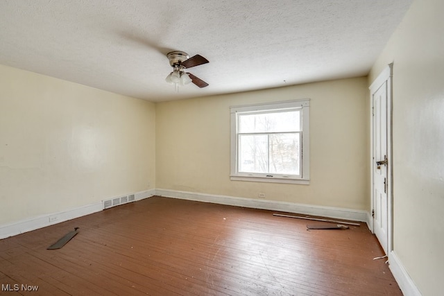 empty room featuring dark hardwood / wood-style flooring, ceiling fan, and a textured ceiling