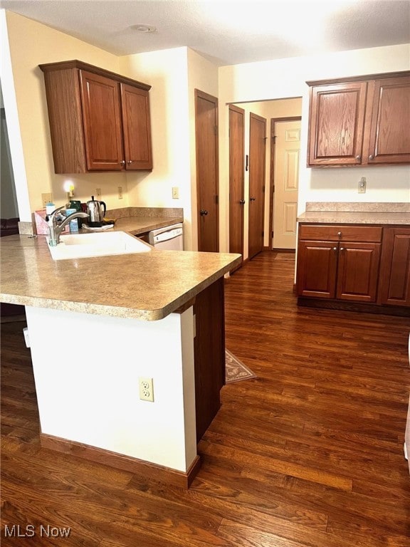 kitchen featuring sink, a kitchen breakfast bar, white dishwasher, dark hardwood / wood-style flooring, and kitchen peninsula