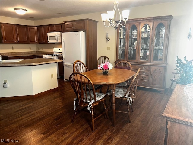 dining space with dark hardwood / wood-style floors, sink, and a notable chandelier