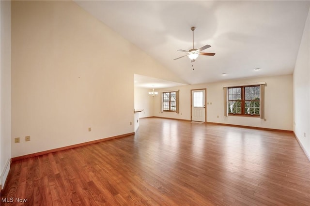 interior space featuring wood-type flooring, ceiling fan with notable chandelier, and high vaulted ceiling