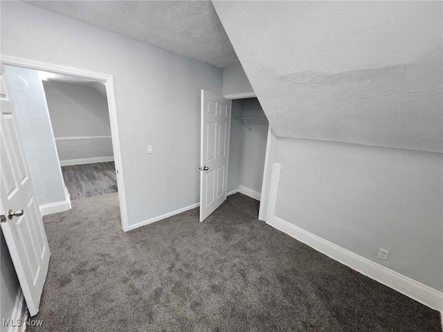 bonus room with dark carpet and a textured ceiling