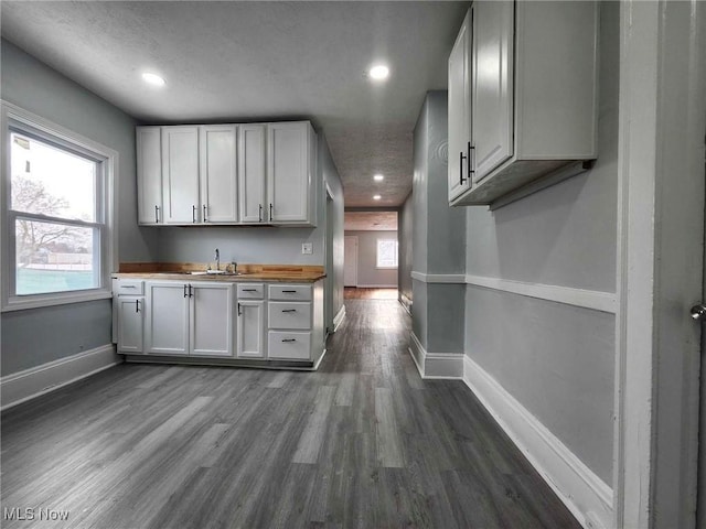 kitchen featuring sink, dark wood-type flooring, wooden counters, and white cabinets