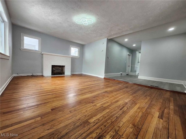 unfurnished living room with a fireplace, a textured ceiling, and light hardwood / wood-style flooring