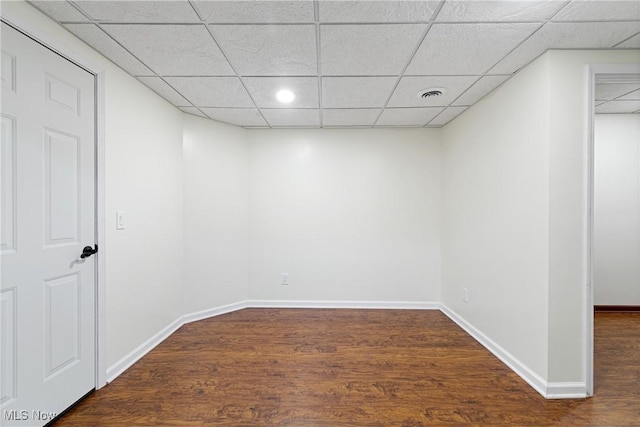 spare room with dark hardwood / wood-style flooring and a drop ceiling