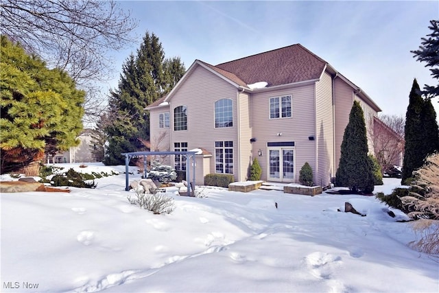 snow covered rear of property with a pergola