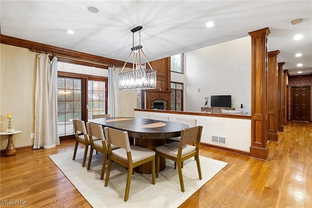 dining area with crown molding, light hardwood / wood-style flooring, and decorative columns