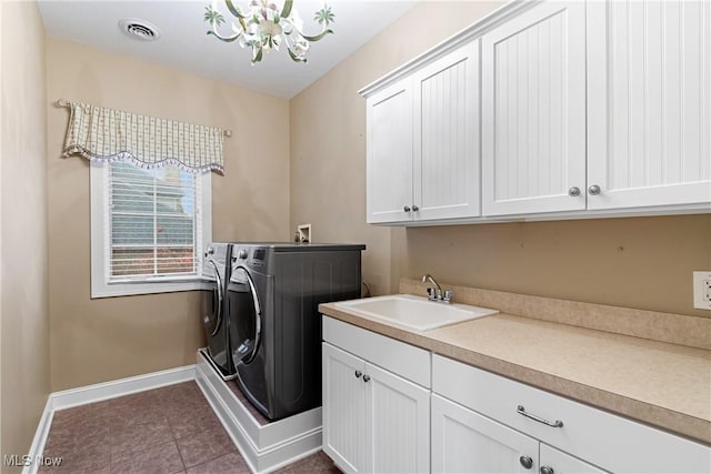 clothes washing area with sink, cabinets, a chandelier, dark tile patterned flooring, and washer and clothes dryer