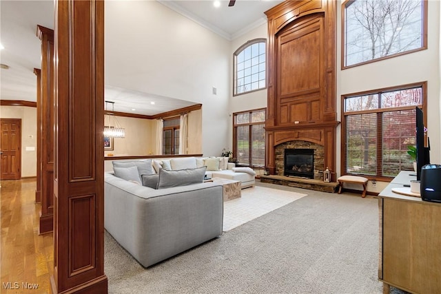 carpeted living room with crown molding, a stone fireplace, and a high ceiling