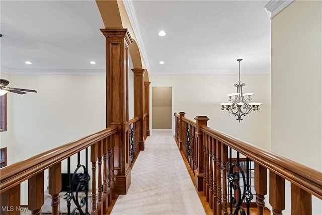 corridor featuring a notable chandelier, crown molding, decorative columns, and carpet flooring