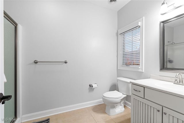 bathroom with tile patterned flooring, vanity, a shower with shower door, and toilet