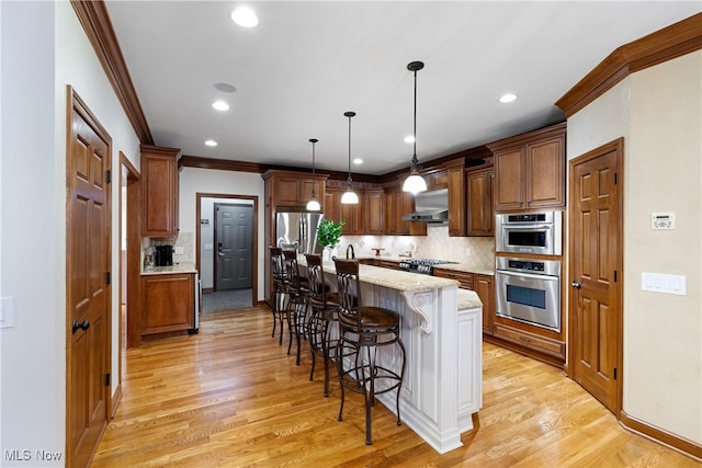 kitchen with a kitchen island, pendant lighting, a kitchen bar, light stone countertops, and wall chimney exhaust hood