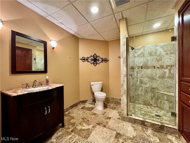 bathroom featuring walk in shower, a paneled ceiling, vanity, and toilet