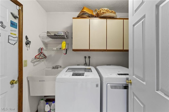 laundry area with cabinets, sink, washing machine and clothes dryer, and a textured ceiling