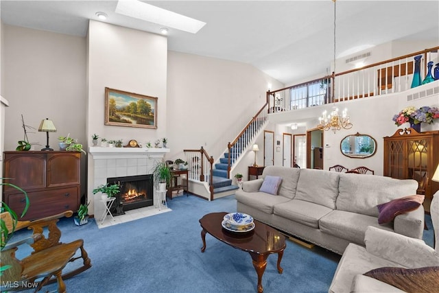 carpeted living room featuring vaulted ceiling with skylight, a fireplace, and an inviting chandelier