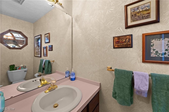 bathroom with vanity, toilet, and a textured ceiling