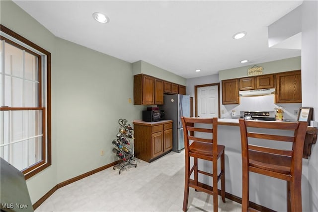 kitchen with a kitchen breakfast bar, stainless steel appliances, kitchen peninsula, and light colored carpet