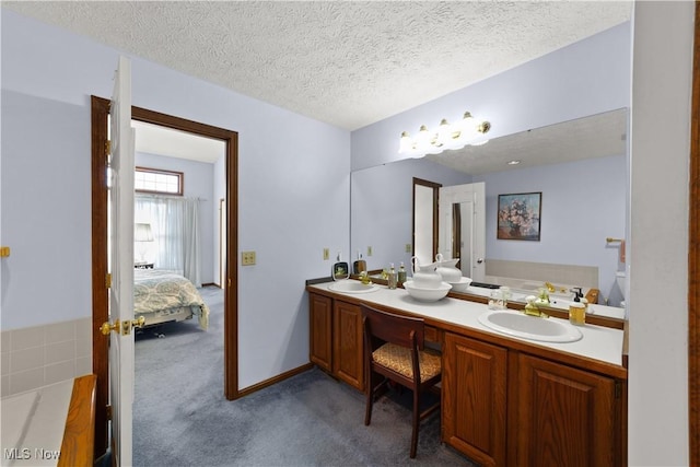 bathroom with vanity, a tub to relax in, and a textured ceiling