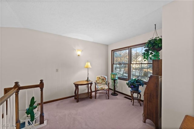 sitting room featuring vaulted ceiling, light colored carpet, and a textured ceiling