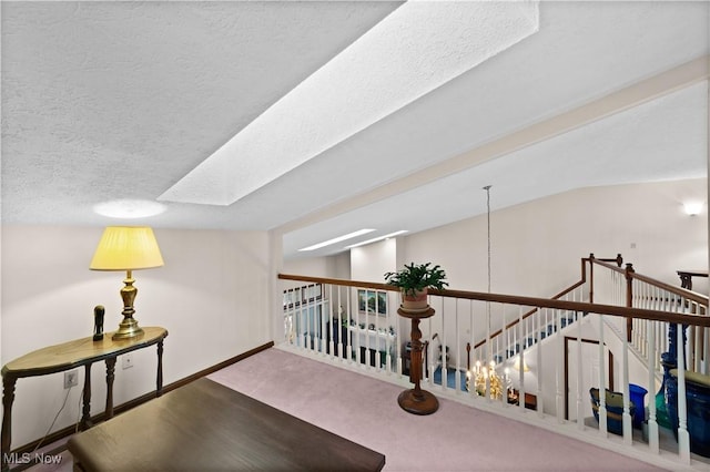 hall featuring lofted ceiling, carpet, and a textured ceiling