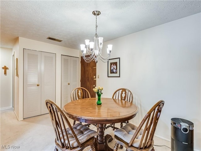 carpeted dining area with a notable chandelier and a textured ceiling