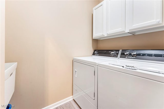 laundry area featuring cabinets, washing machine and clothes dryer, and light hardwood / wood-style floors