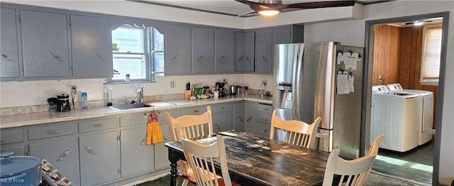 kitchen with stainless steel refrigerator with ice dispenser, sink, gray cabinetry, and washer and clothes dryer