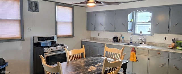 kitchen with gas stove, sink, gray cabinetry, and ceiling fan