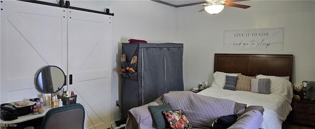 bedroom with crown molding, a barn door, and ceiling fan