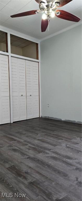 unfurnished bedroom featuring dark wood-type flooring, ornamental molding, a closet, and ceiling fan