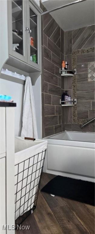 bathroom featuring hardwood / wood-style floors and washtub / shower combination