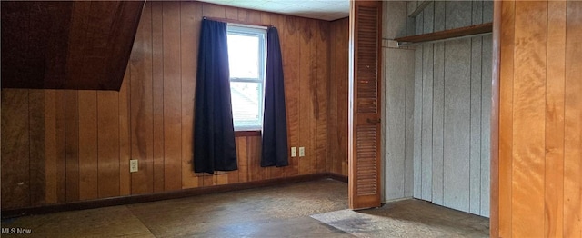 unfurnished bedroom with a closet and wood walls