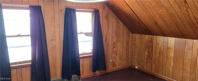 additional living space with lofted ceiling and wood walls