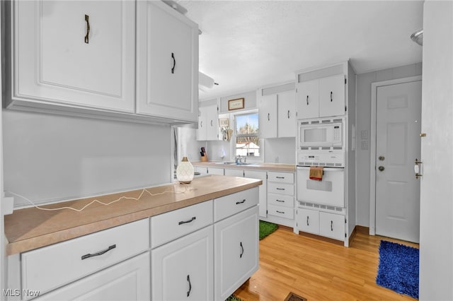 kitchen featuring white cabinetry, white appliances, and light wood-type flooring